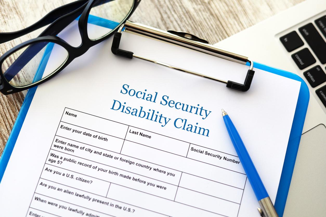 Social Security Disability form on blue clipboard with pen resting on it